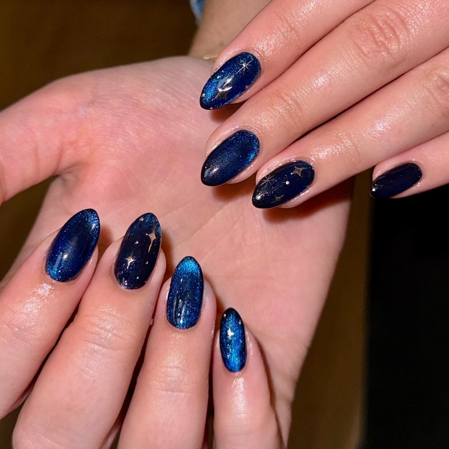10. Midnight Galaxy Blue with Gold Stardust (Winter Almond Nail Ideas)