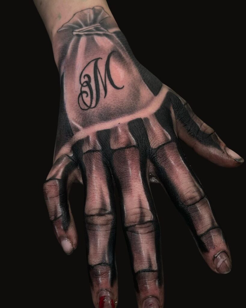 Bone Hand, Sack And Letter M Tattoo