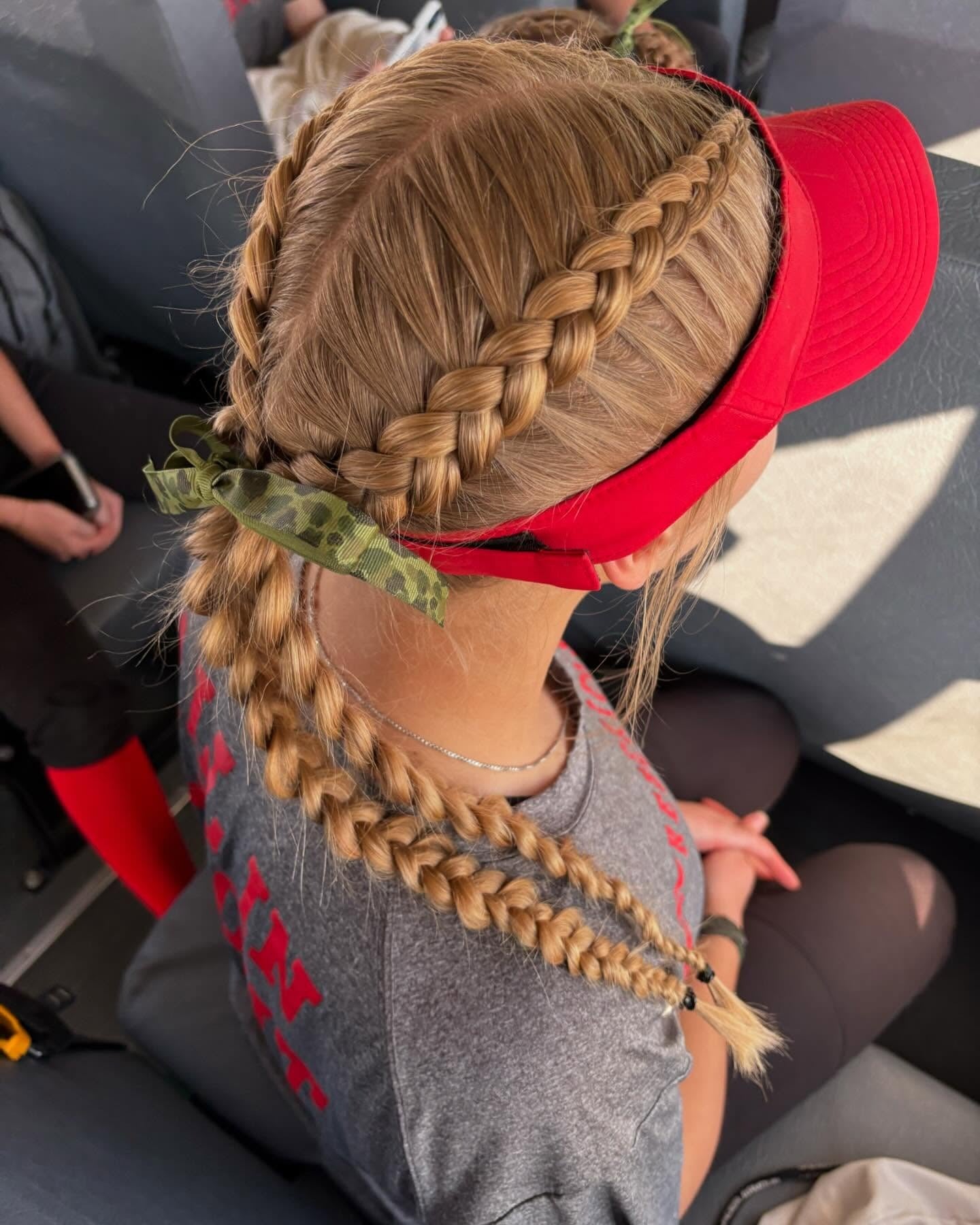 8. Dutch Braids with Visor and Green Ribbon Accent (Softball Hairstyles)