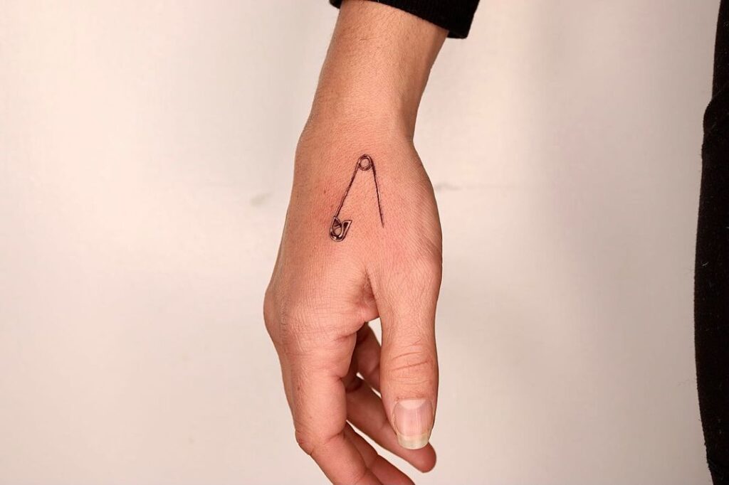 Small Safety Pin Hand Tattoo