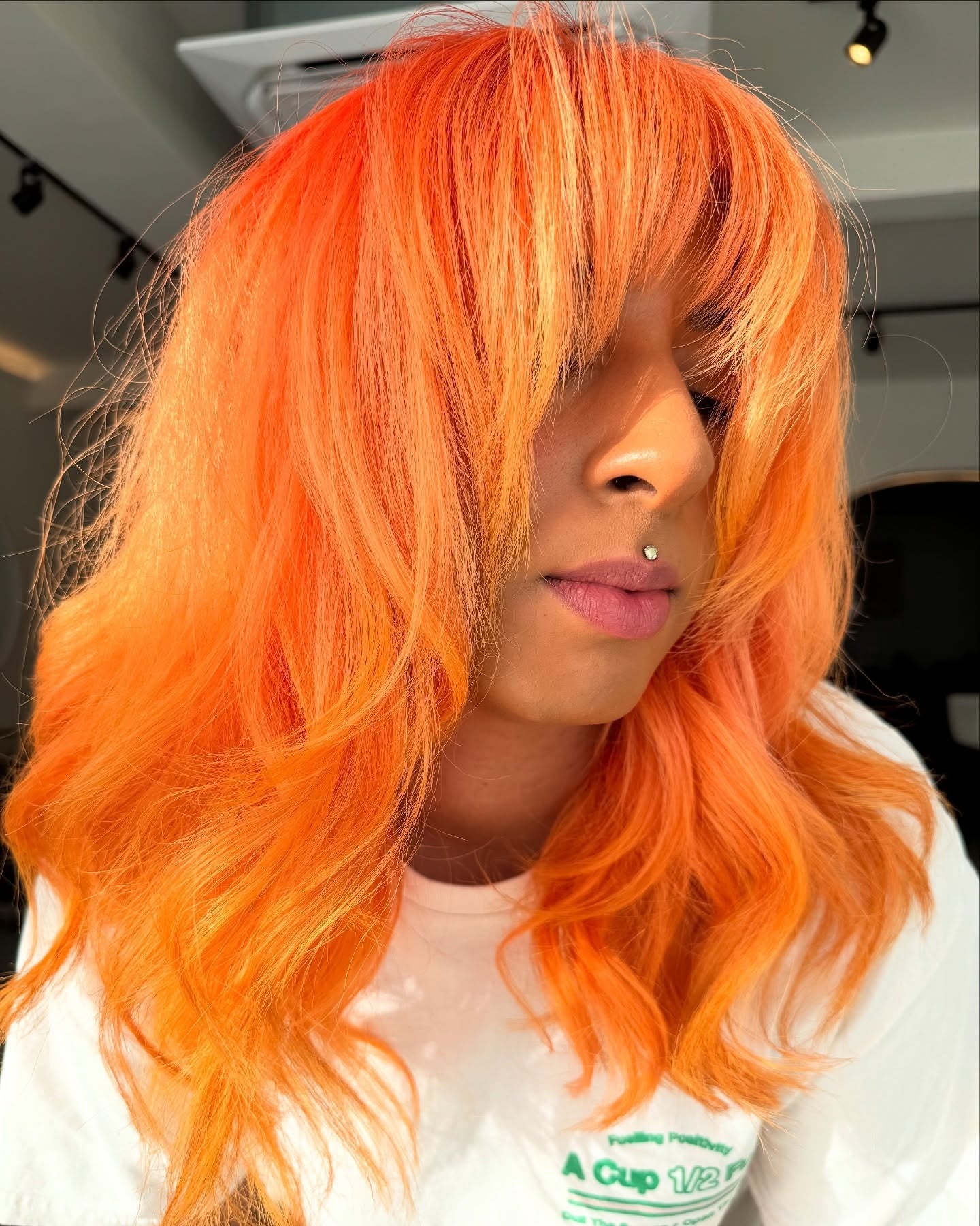 9. Electric Orange with Voluminous Curtain Bangs (Orange Hair Color)