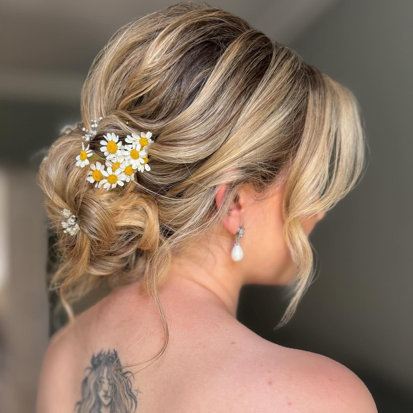 12. Low Textured Bun with Daisy Accents (Wedding Hairstyles)