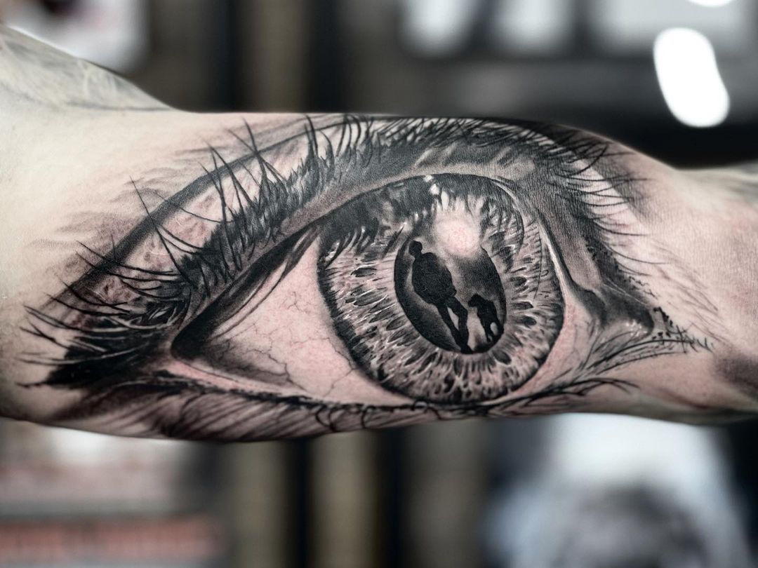 Bicep Tattoo eye with man and dog - Black Rose Tattoo Shop