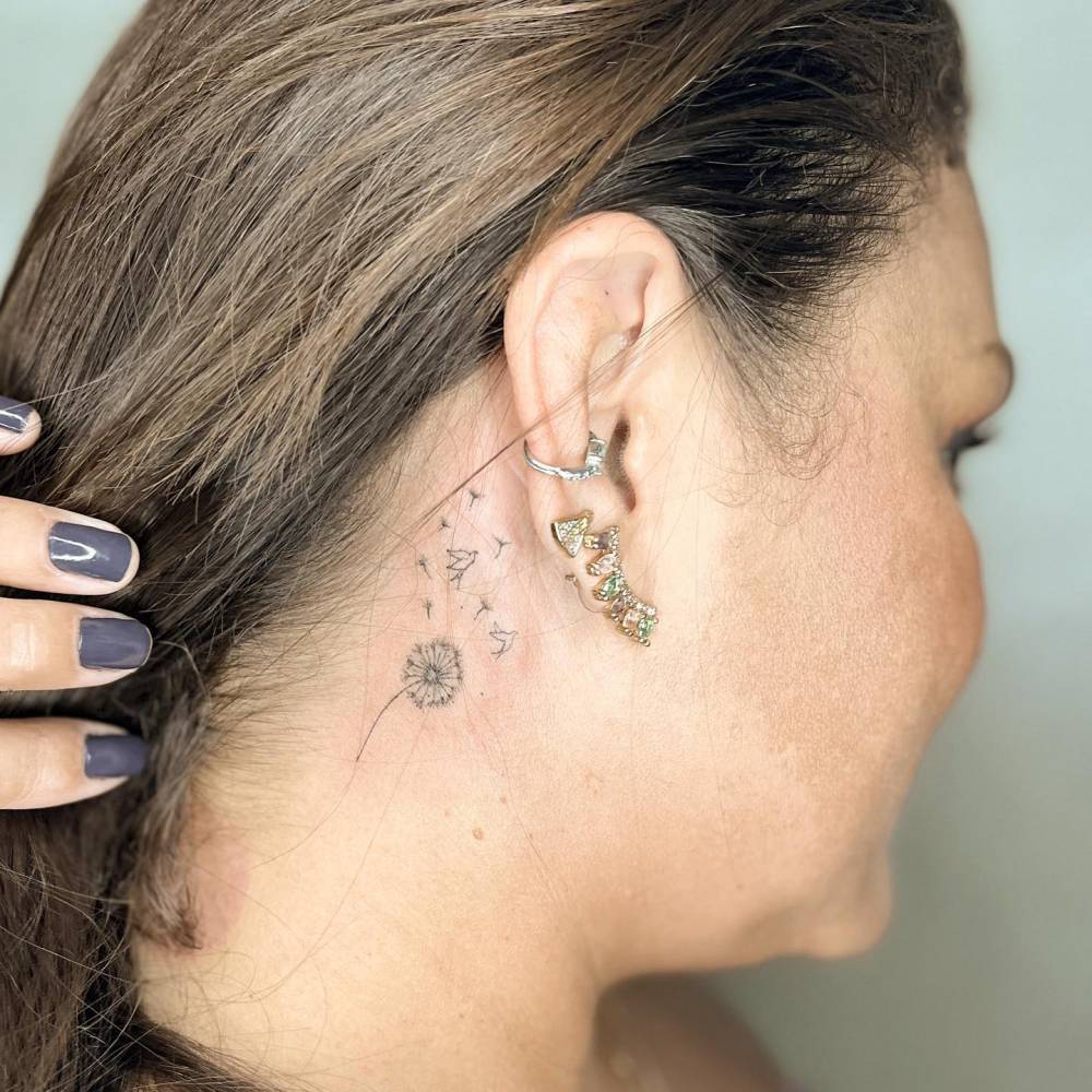 Dandelion seeds tattooed behind the ear, fine line