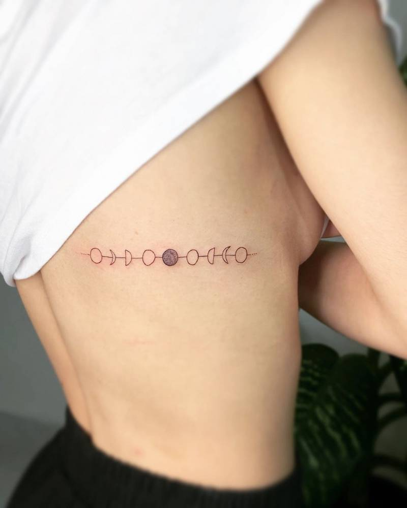 Minimalist moon phases tattoo on the rib.