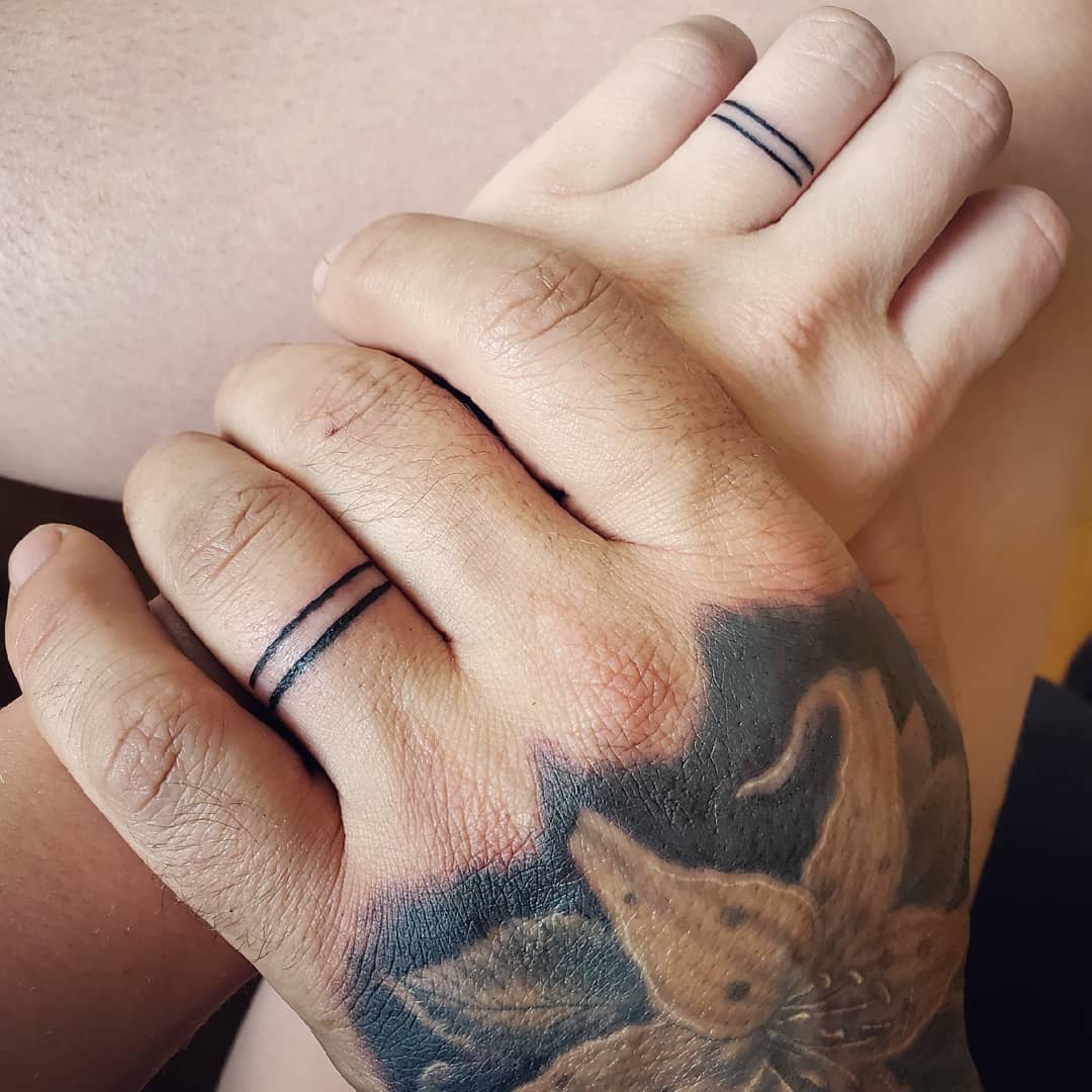 Minimalist wedding ring tattoos on couple's hands