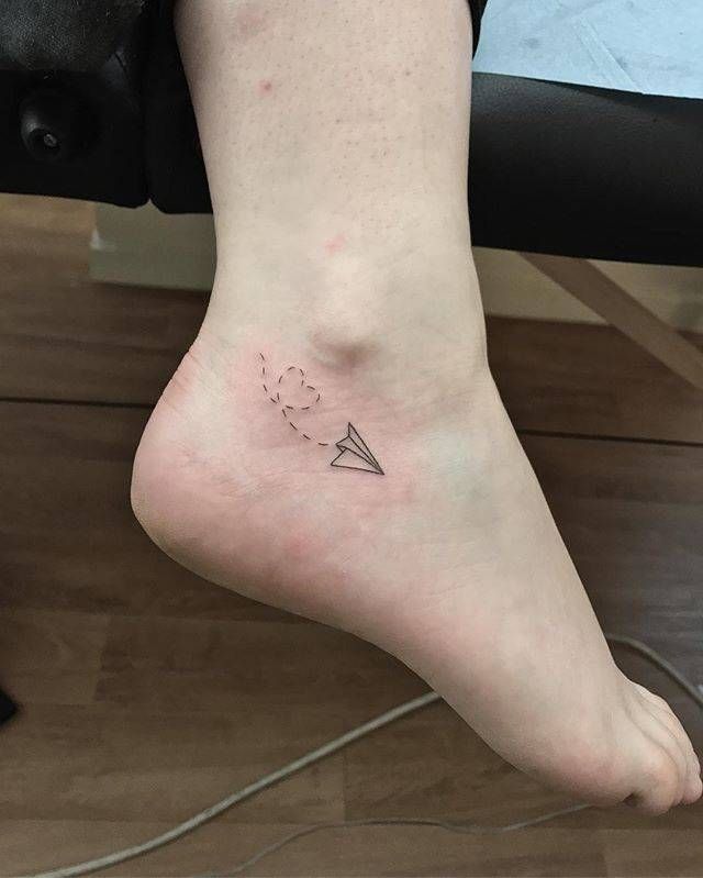 Paper plane tattoo on the ankle.