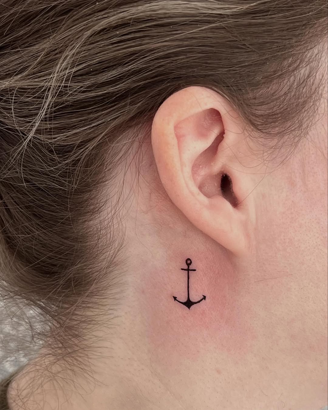 Sleek anchor tattoo behind the ear