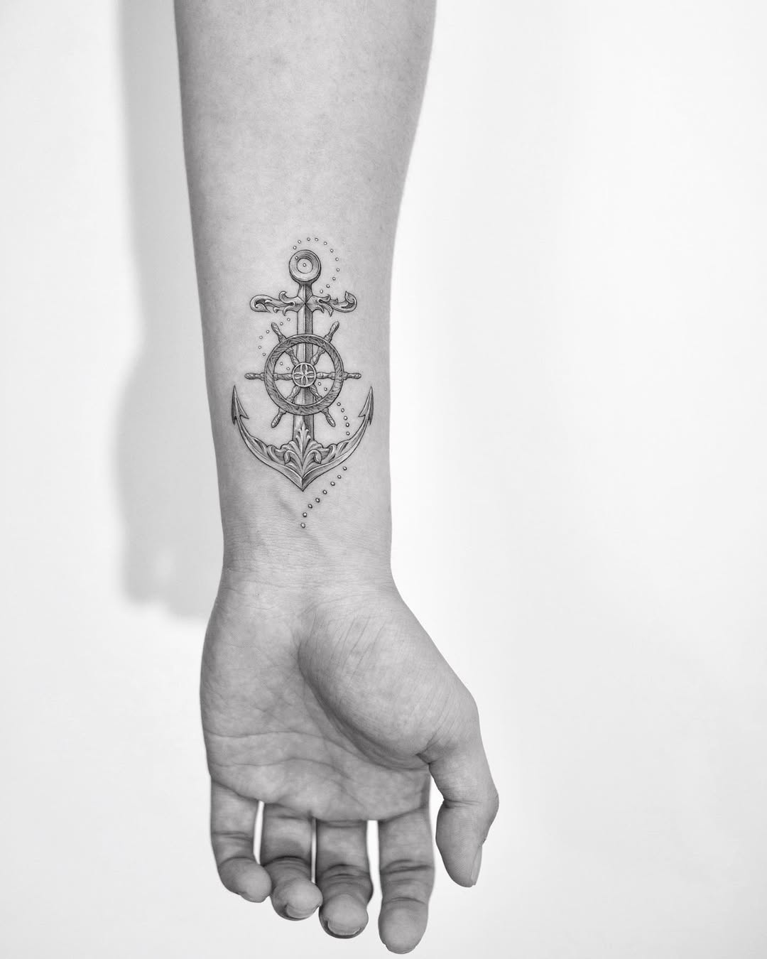 Stylish anchor and wheel tattoo on forearm
