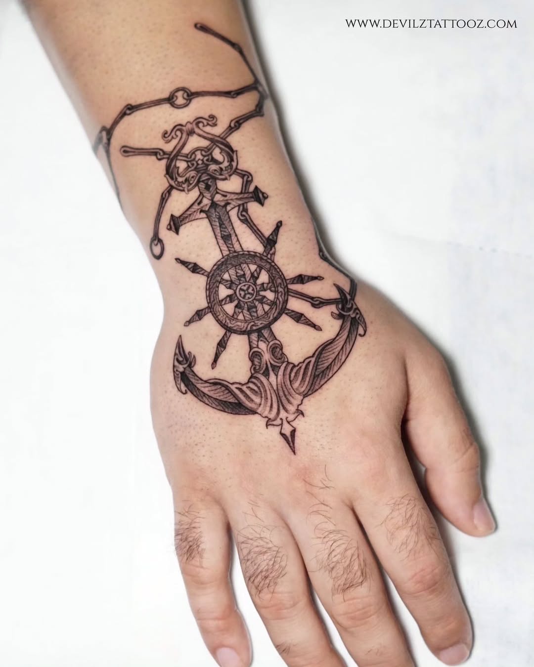 Intricate anchor tattoo with skull and ship wheel