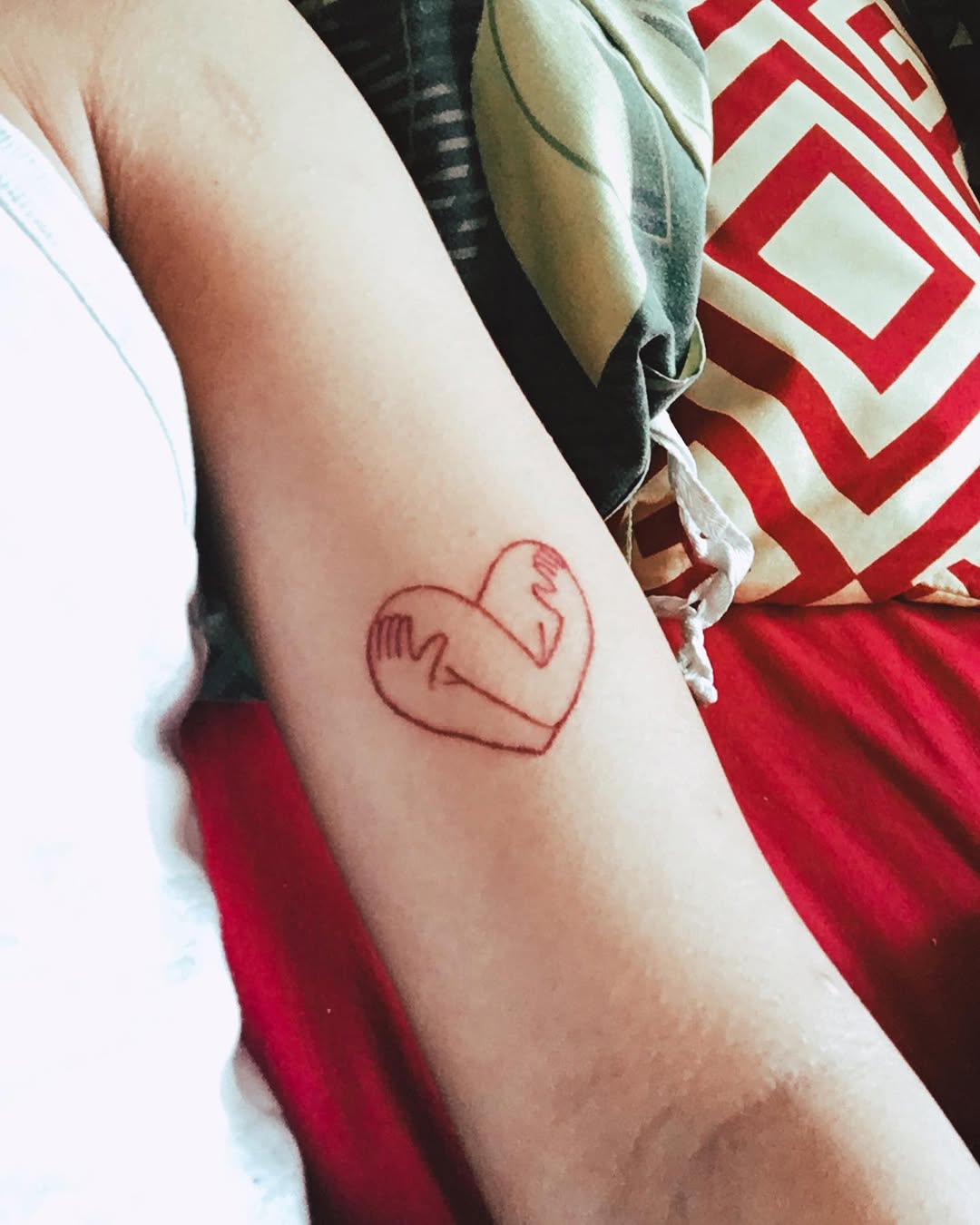 A heart embraced by hands tattoo design