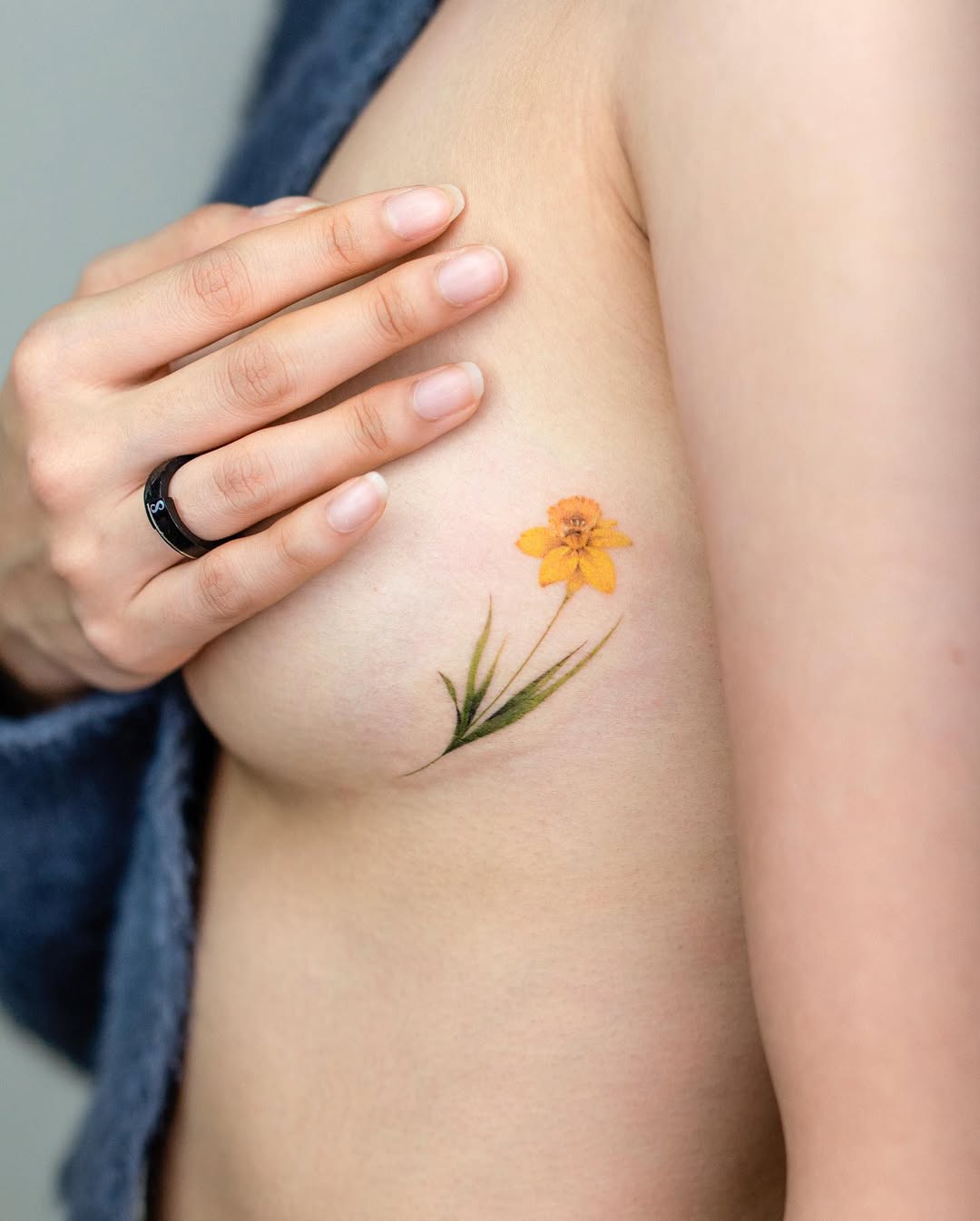 Vibrant yellow floral underboob tattoo design