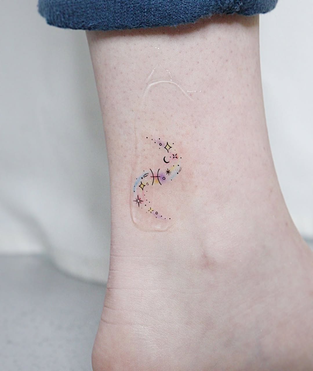 Minimalist watercolor Pisces tattoo with stars