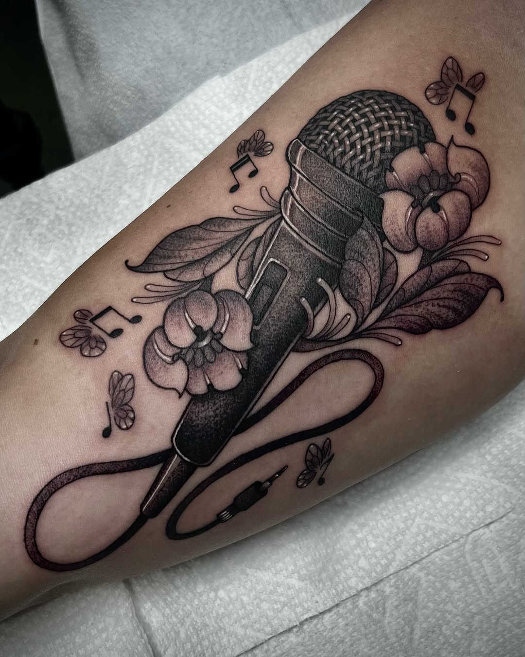 Elegant microphone tattoo surrounded by floral elements