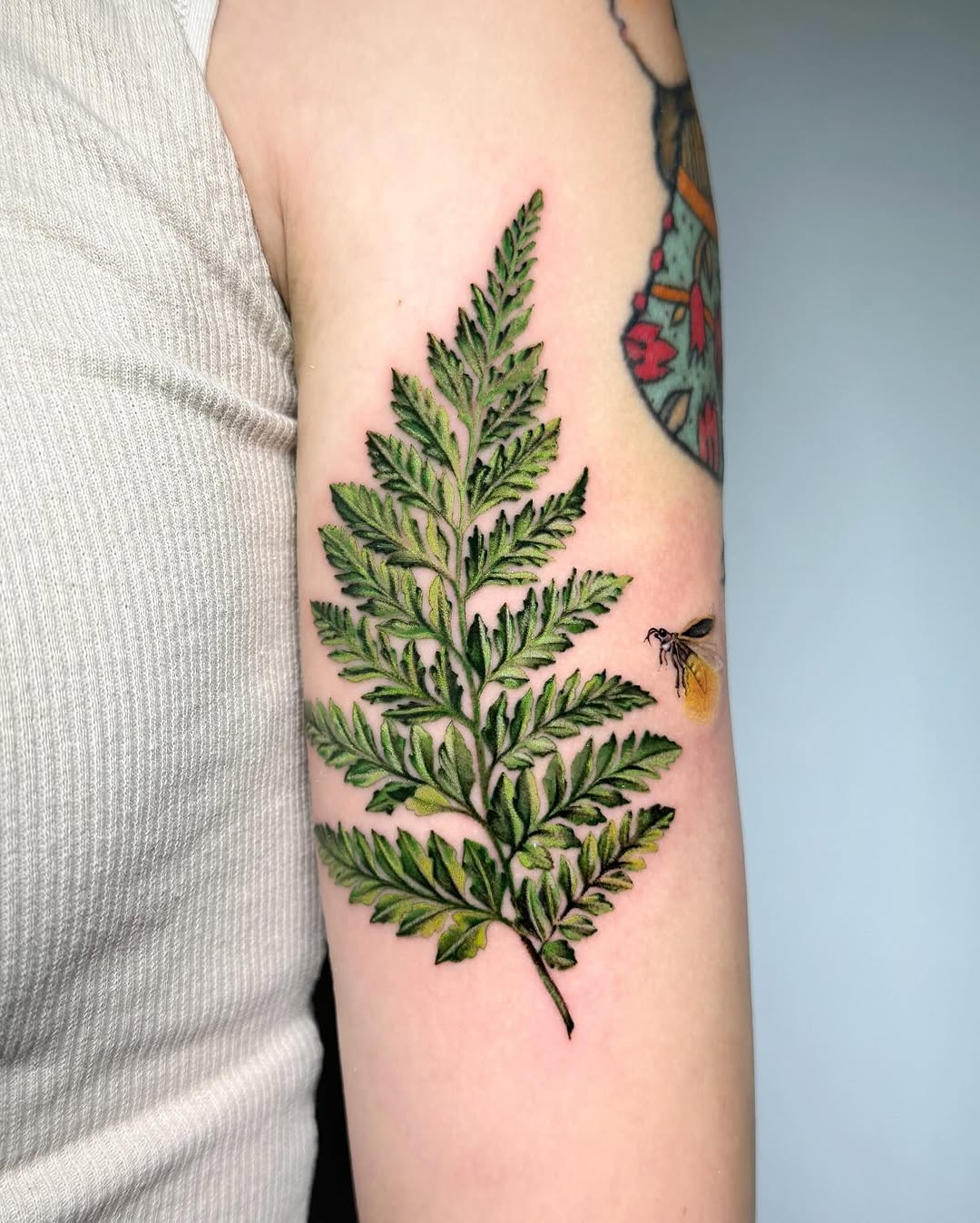 Nature-inspired firefly tattoo with fern design