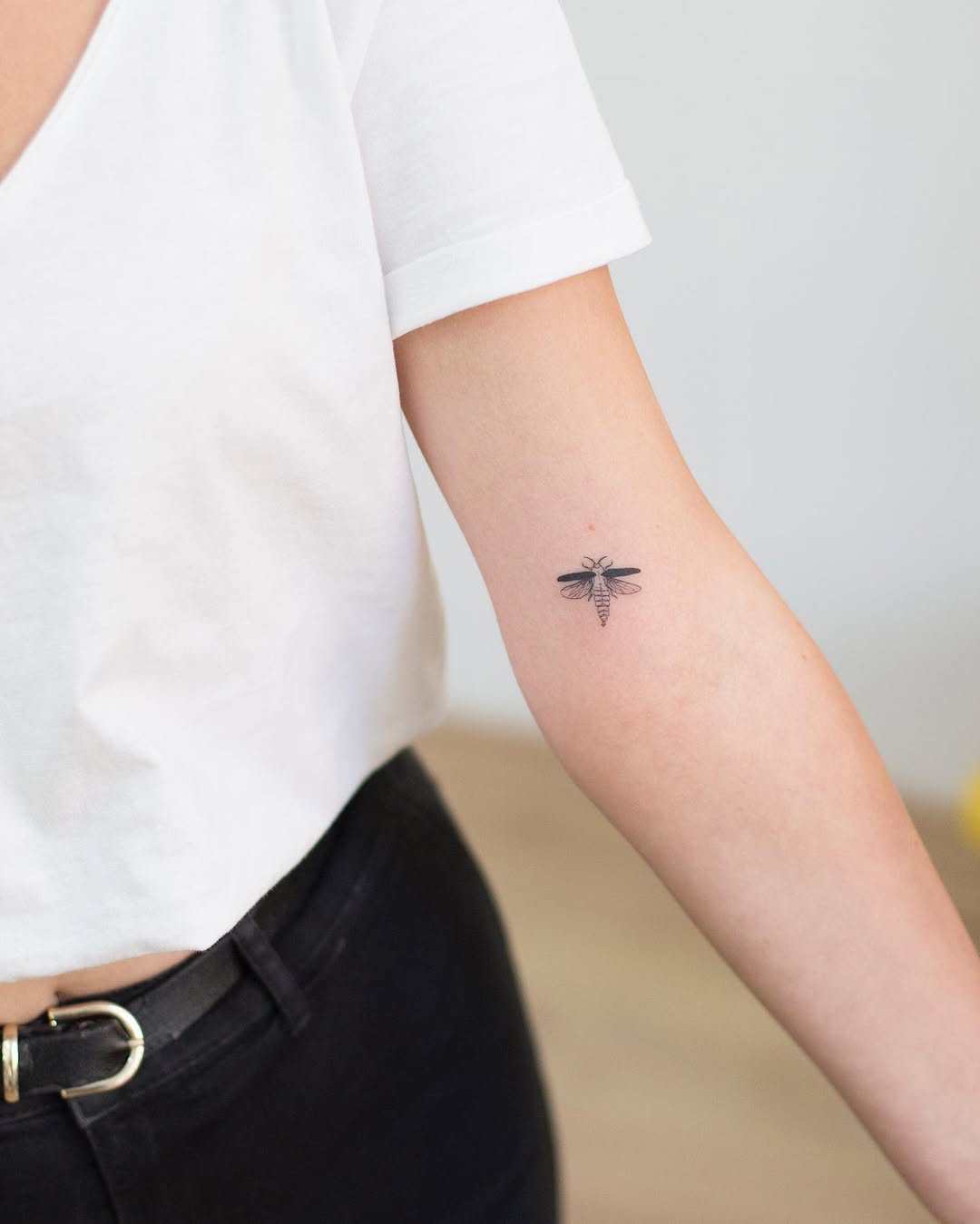 Elegant small firefly tattoo on the forearm