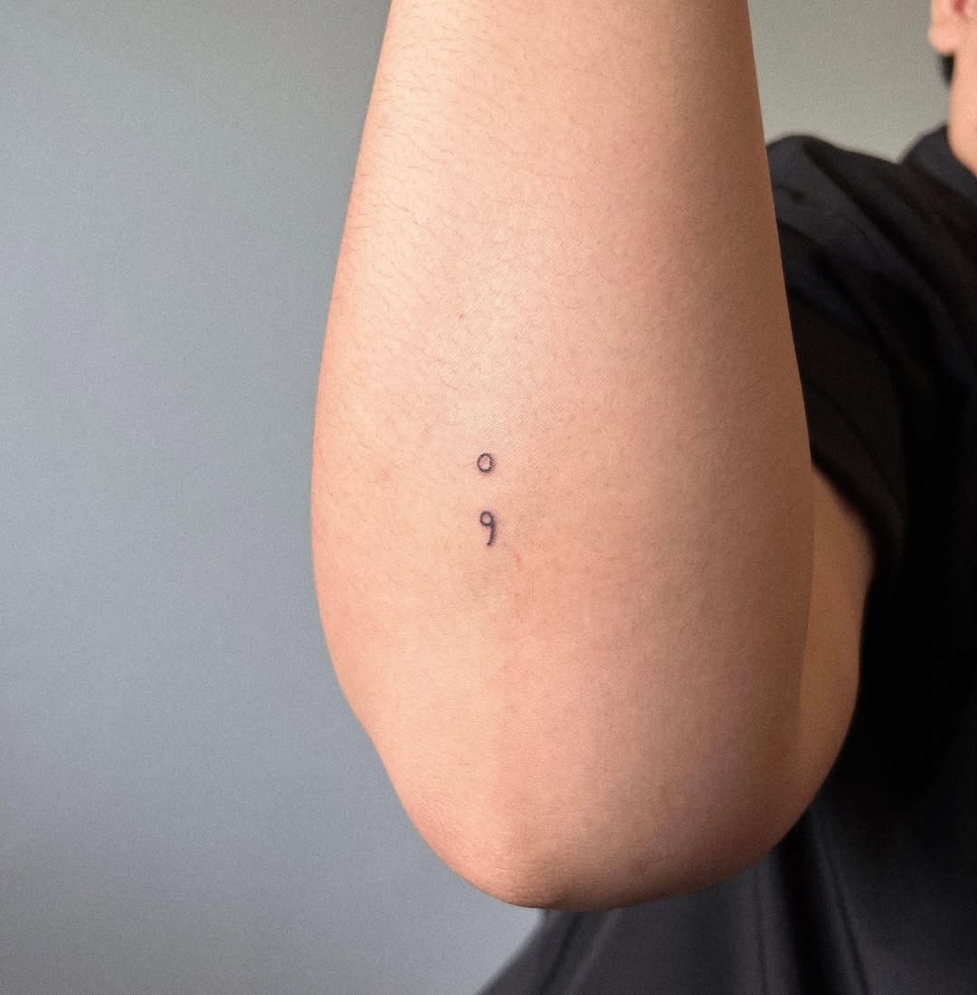 Minimalist semicolon tattoo on the elbow