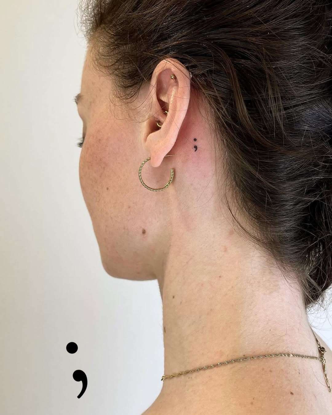 Stylish semicolon tattoo near the ear