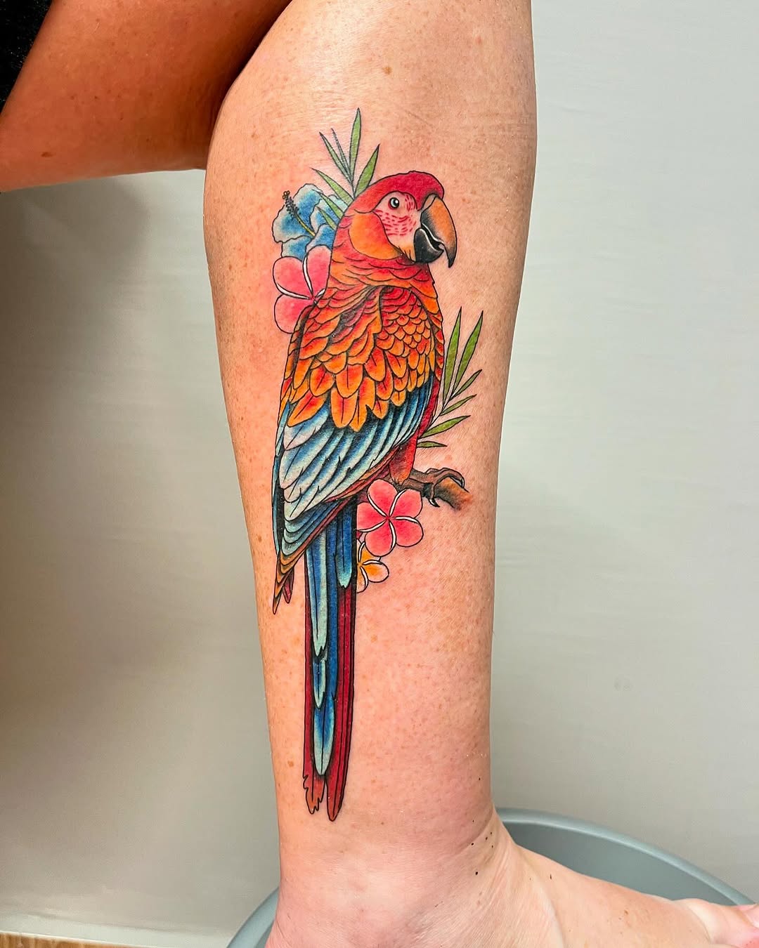 Vibrant parrot tattoo with floral accents