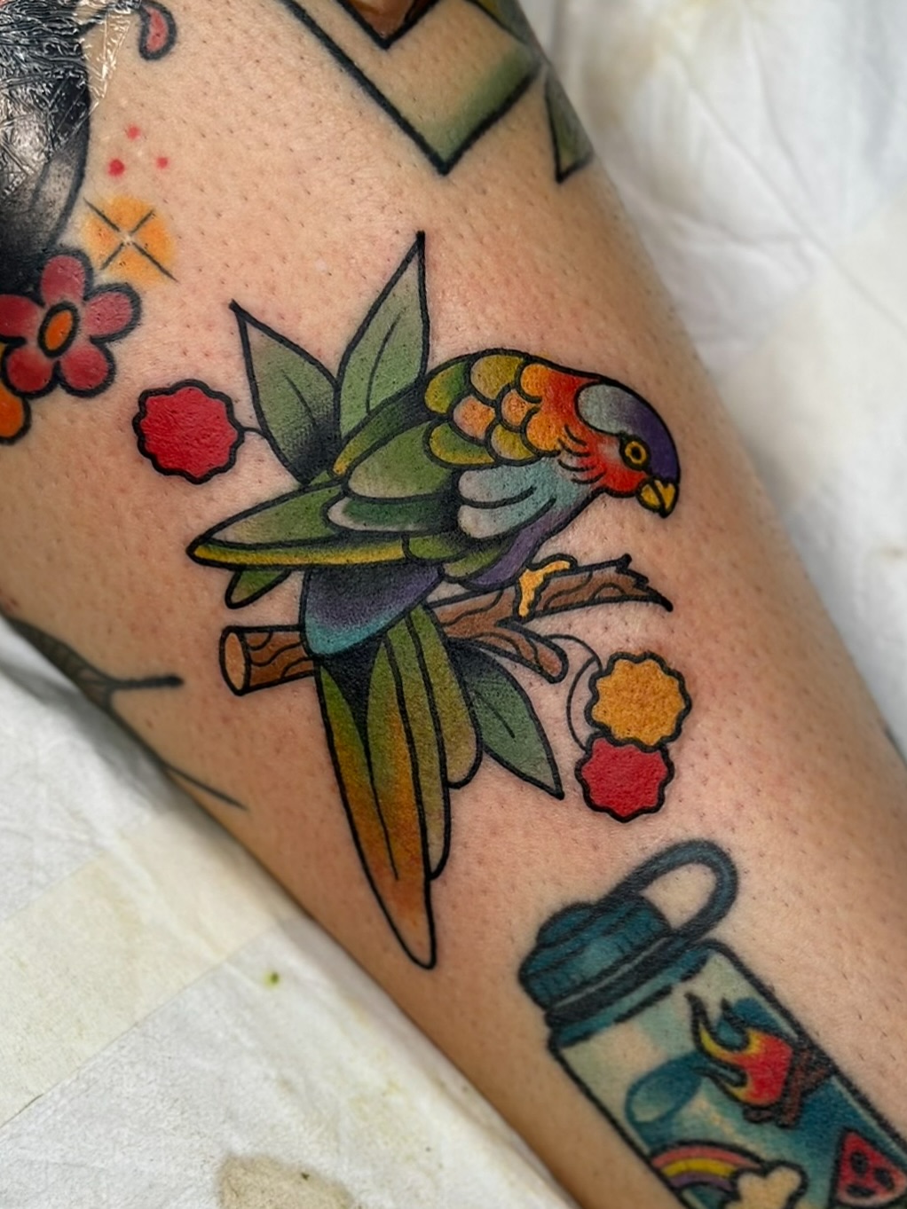 Colorful parrot tattoo perched on a branch