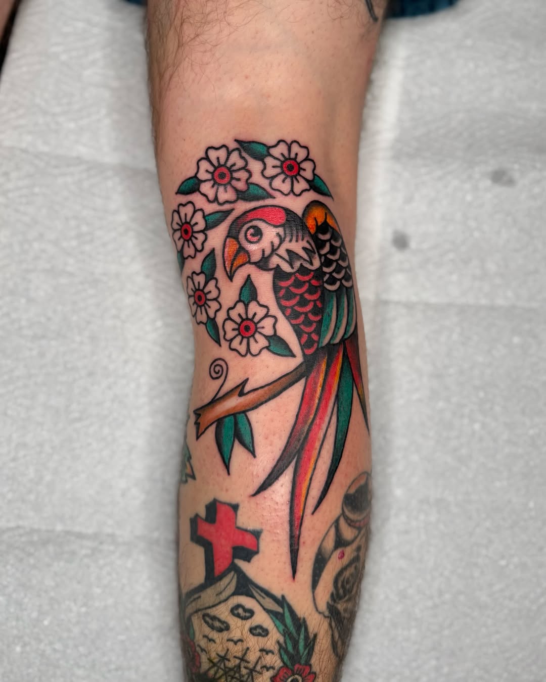 Vibrant parrot tattoo adorned with blossoms