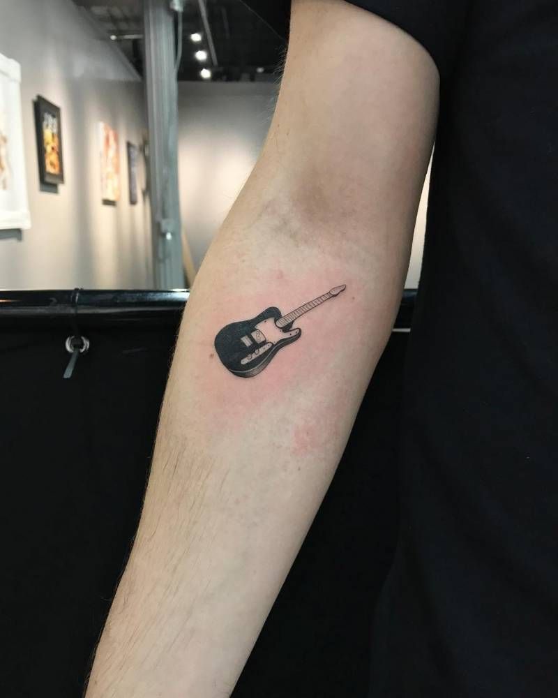 Small guitar tattoo on the right inner forearm.