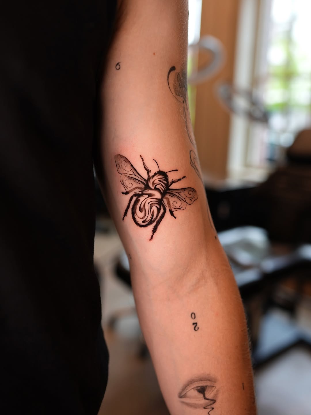 Elegant bee tattoo design on woman's arm