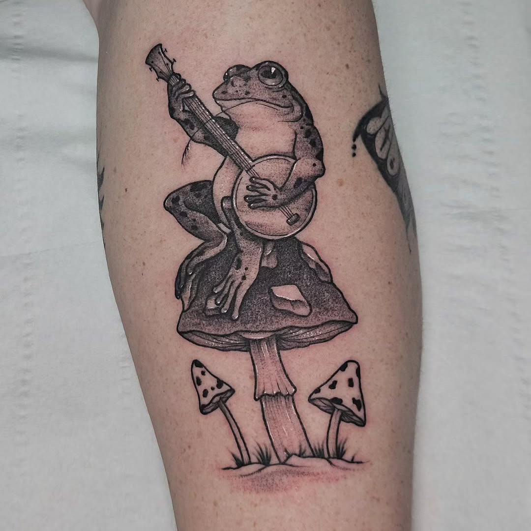 Whimsical frog tattoo playing a guitar