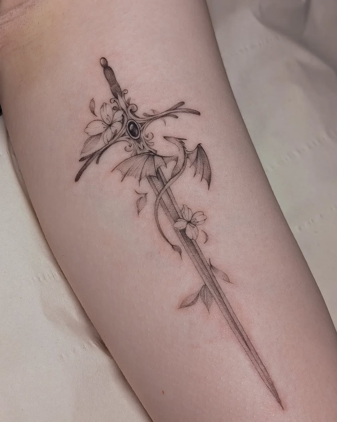 Intricate sword tattoo with floral elements