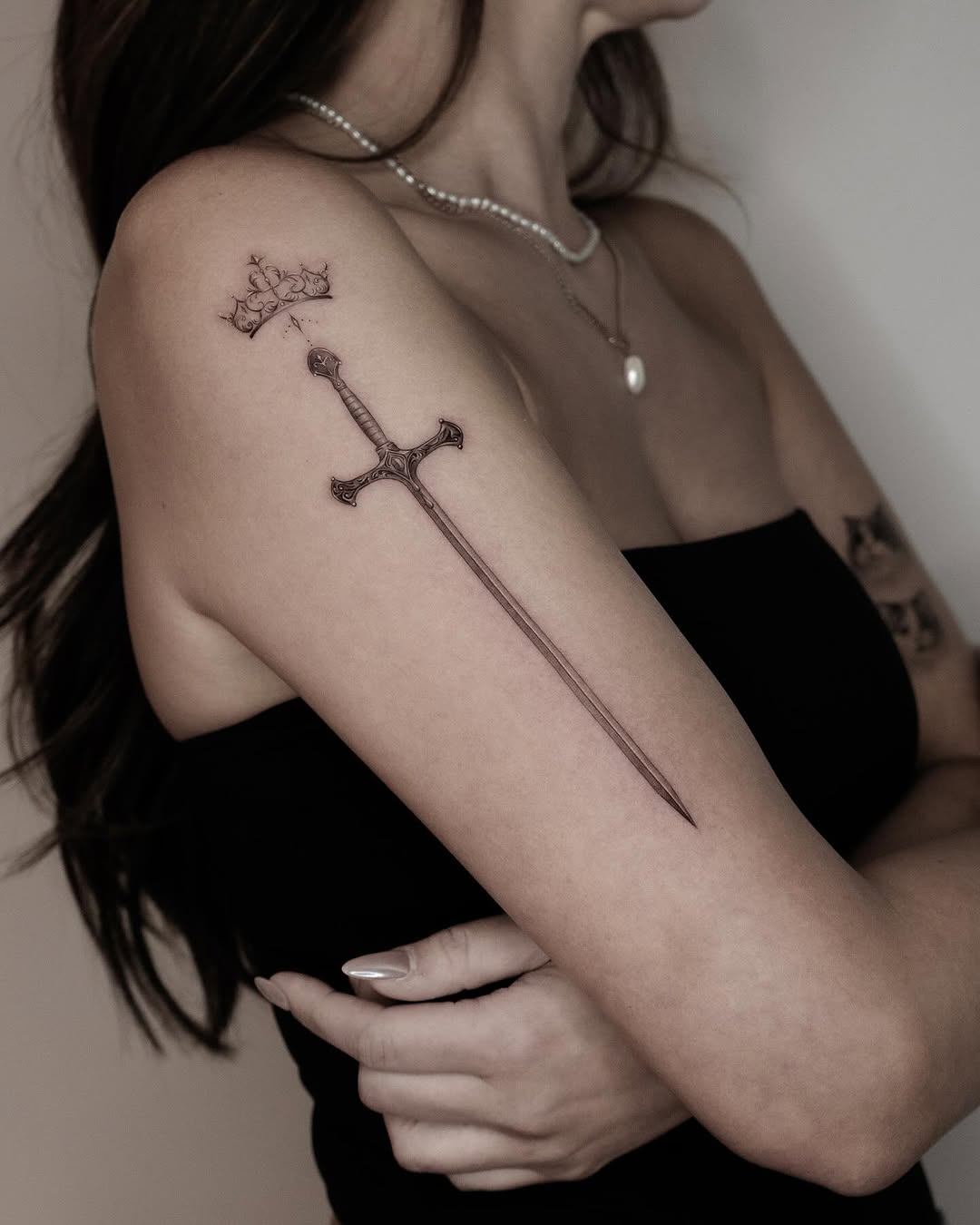 Elegant sword tattoo with a crown design