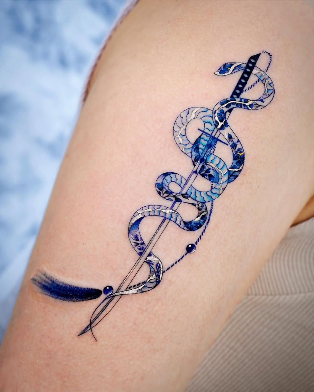 Unique blue snake entwined sword tattoo