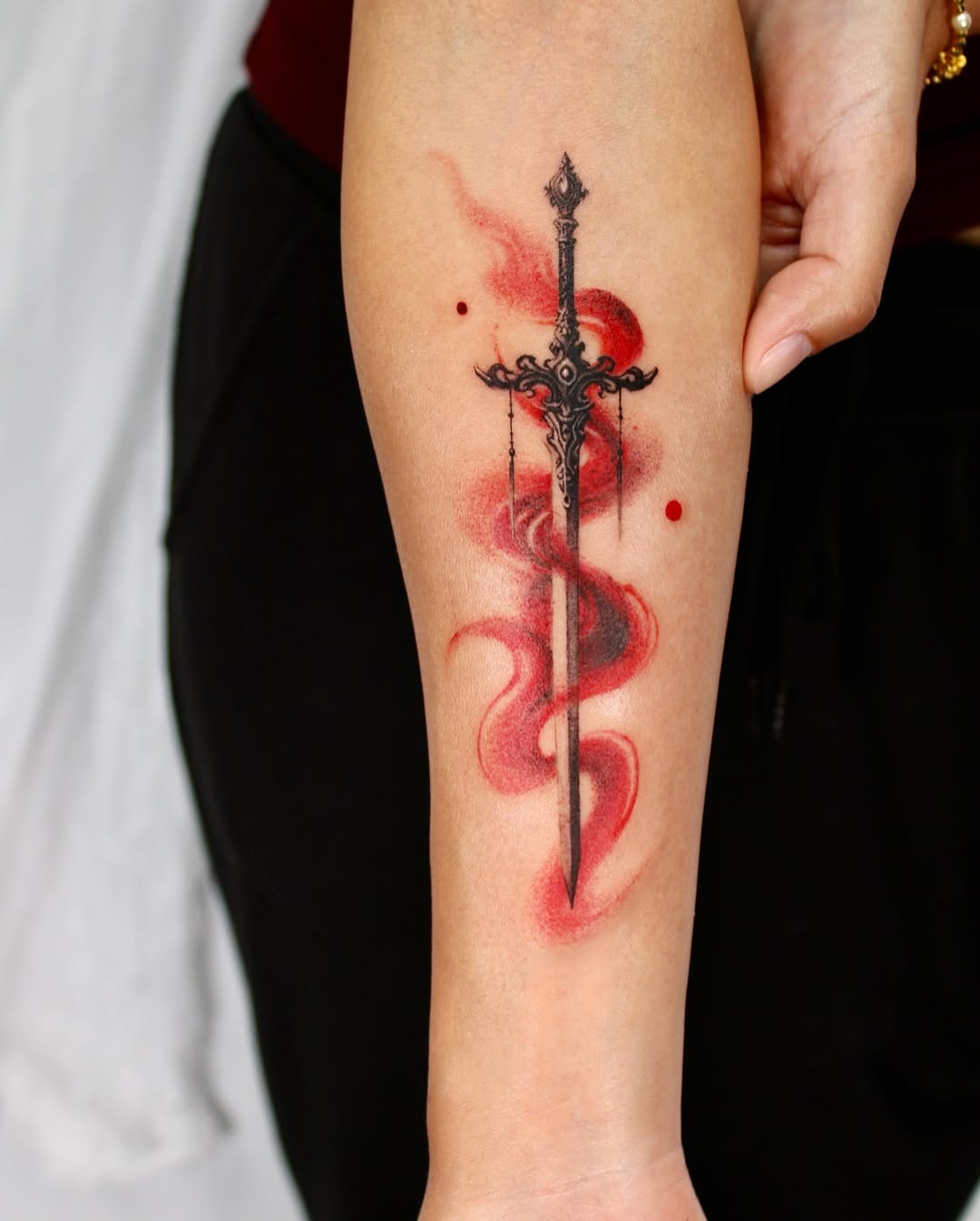 Intricate sword tattoo with vibrant red swirls