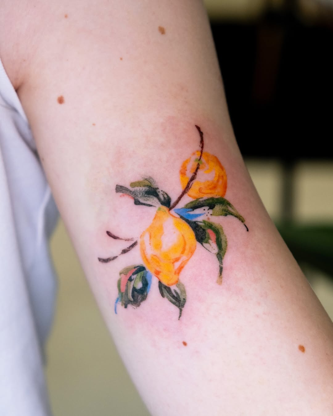 Vibrant lemon tattoo with floral accents