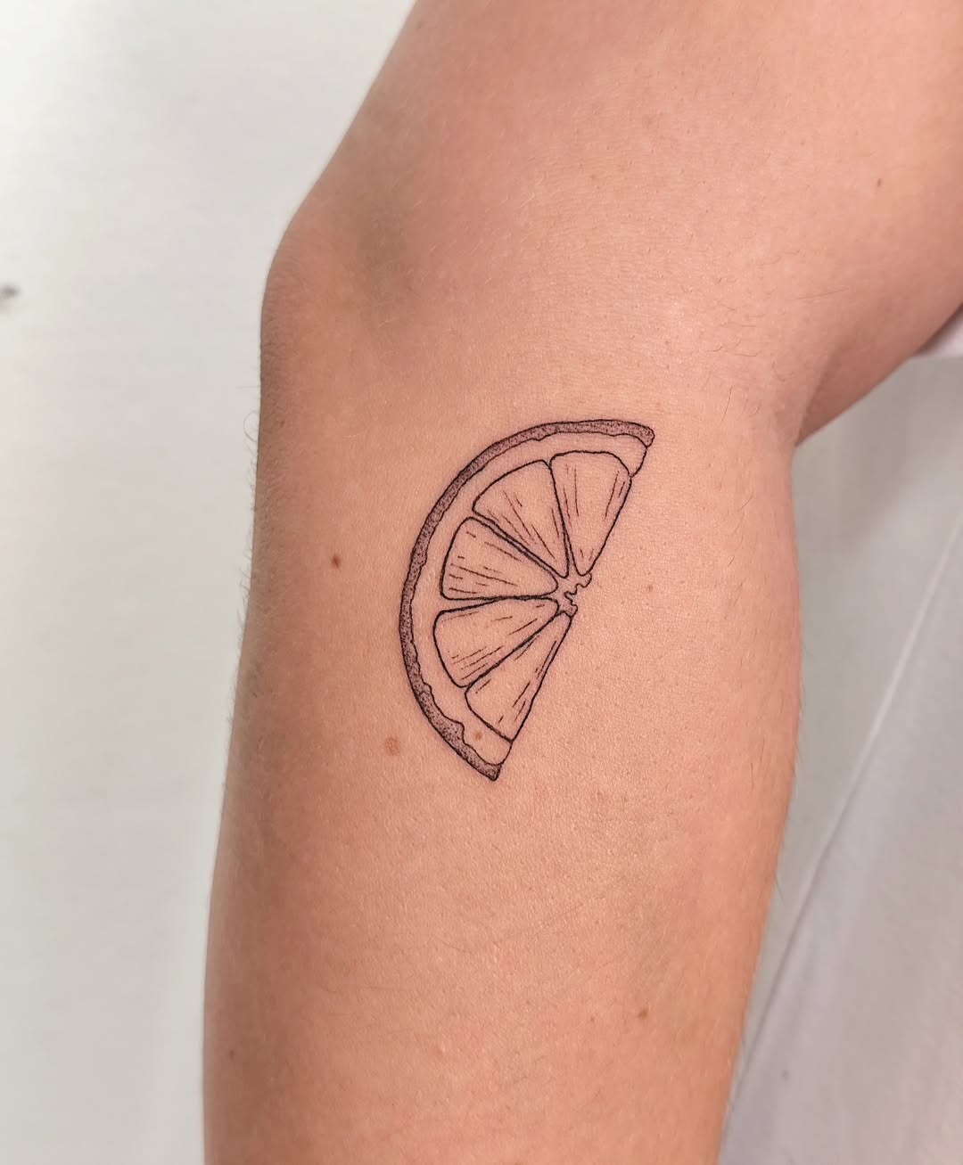 Minimalist lemon slice tattoo on the arm