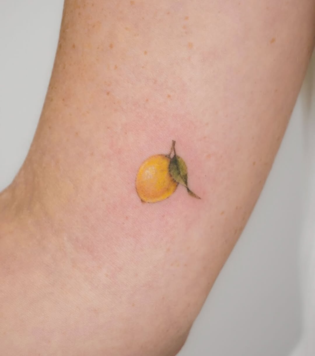 Charming lemon tattoo on a delicate arm