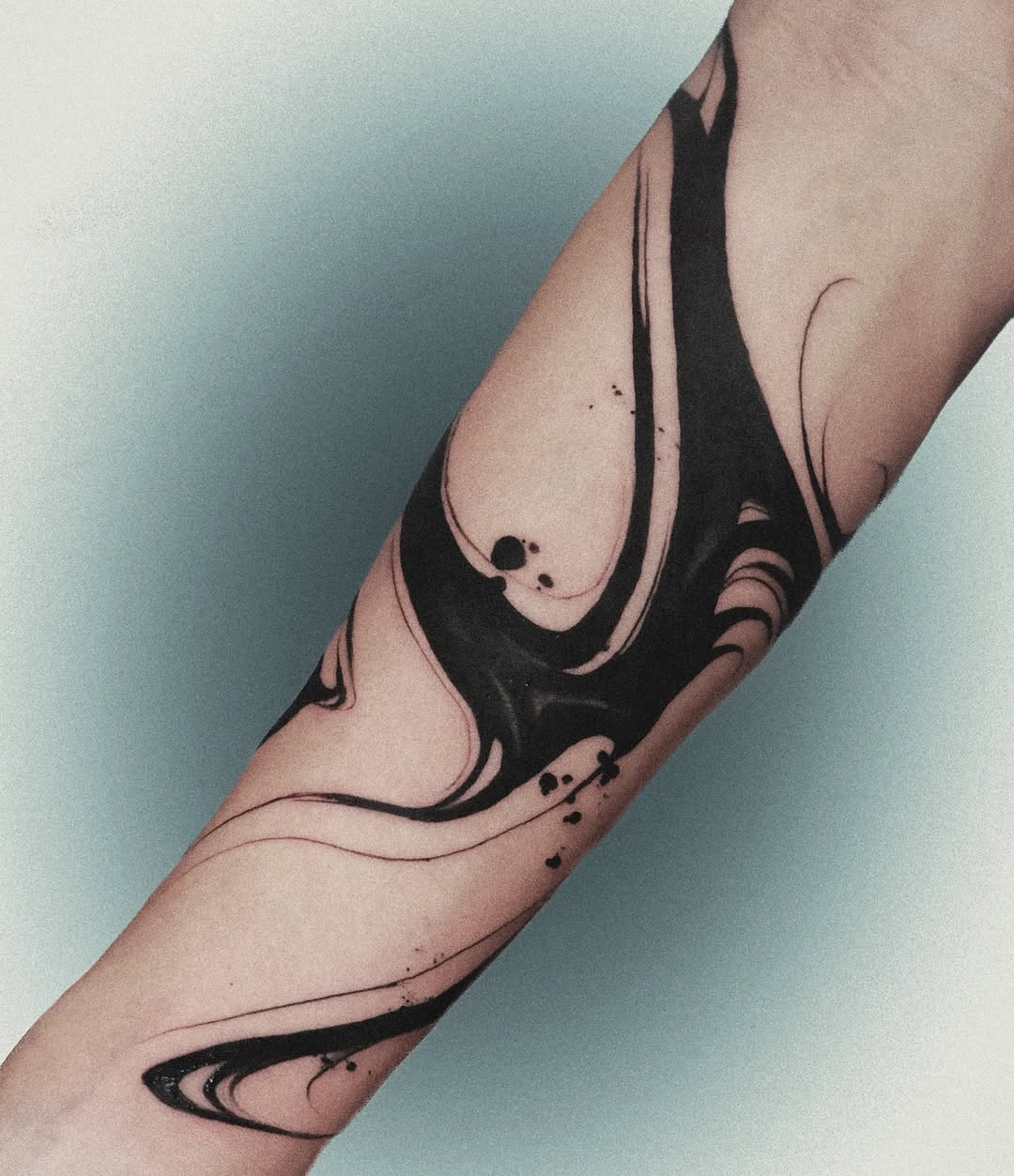 Fluid black waves adorn this arm tattoo