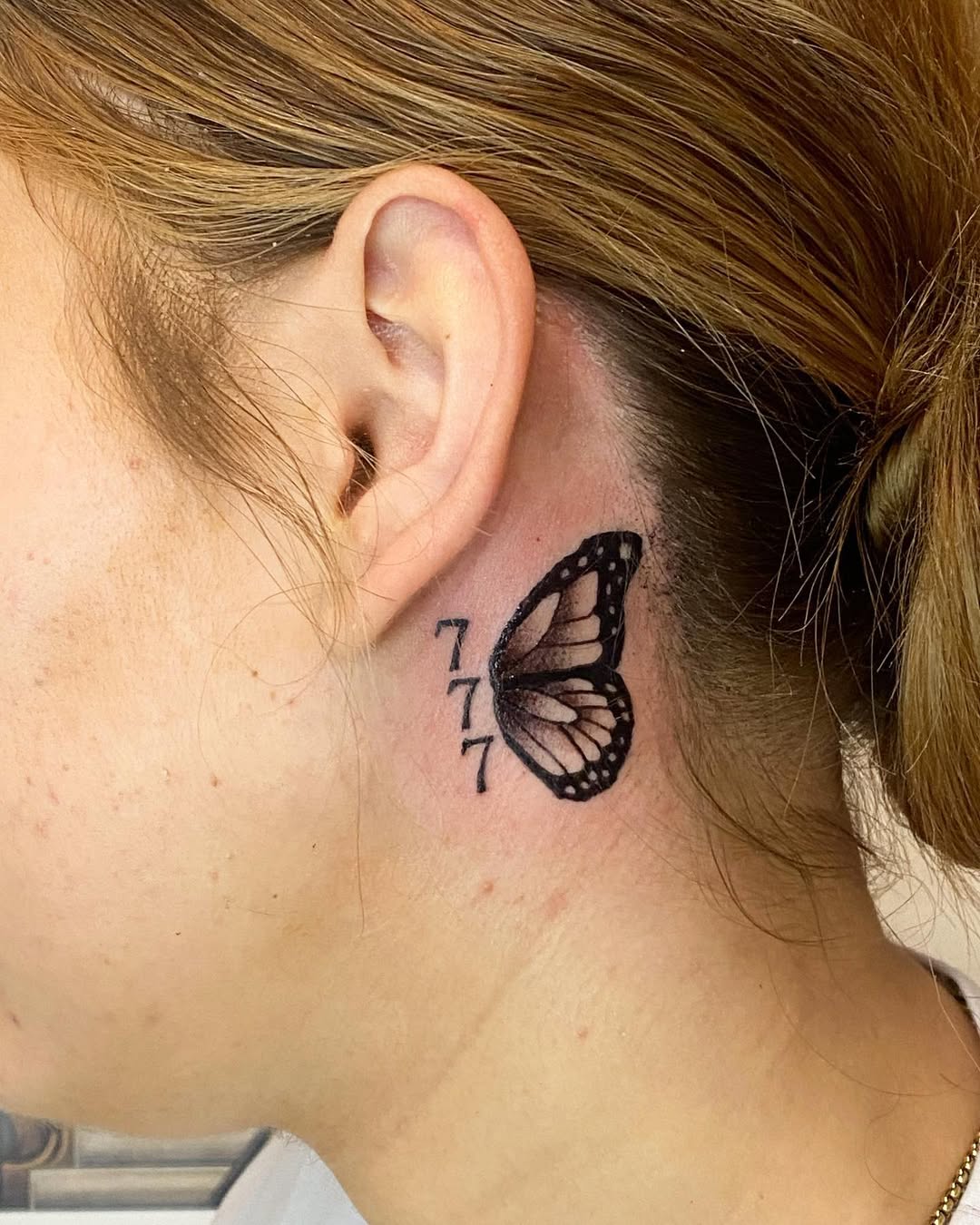 Symbolic butterfly inked near the ear