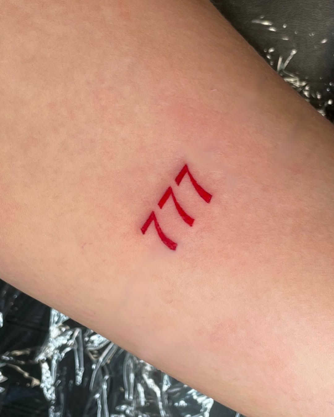 Minimalist red 777 tattoo on skin