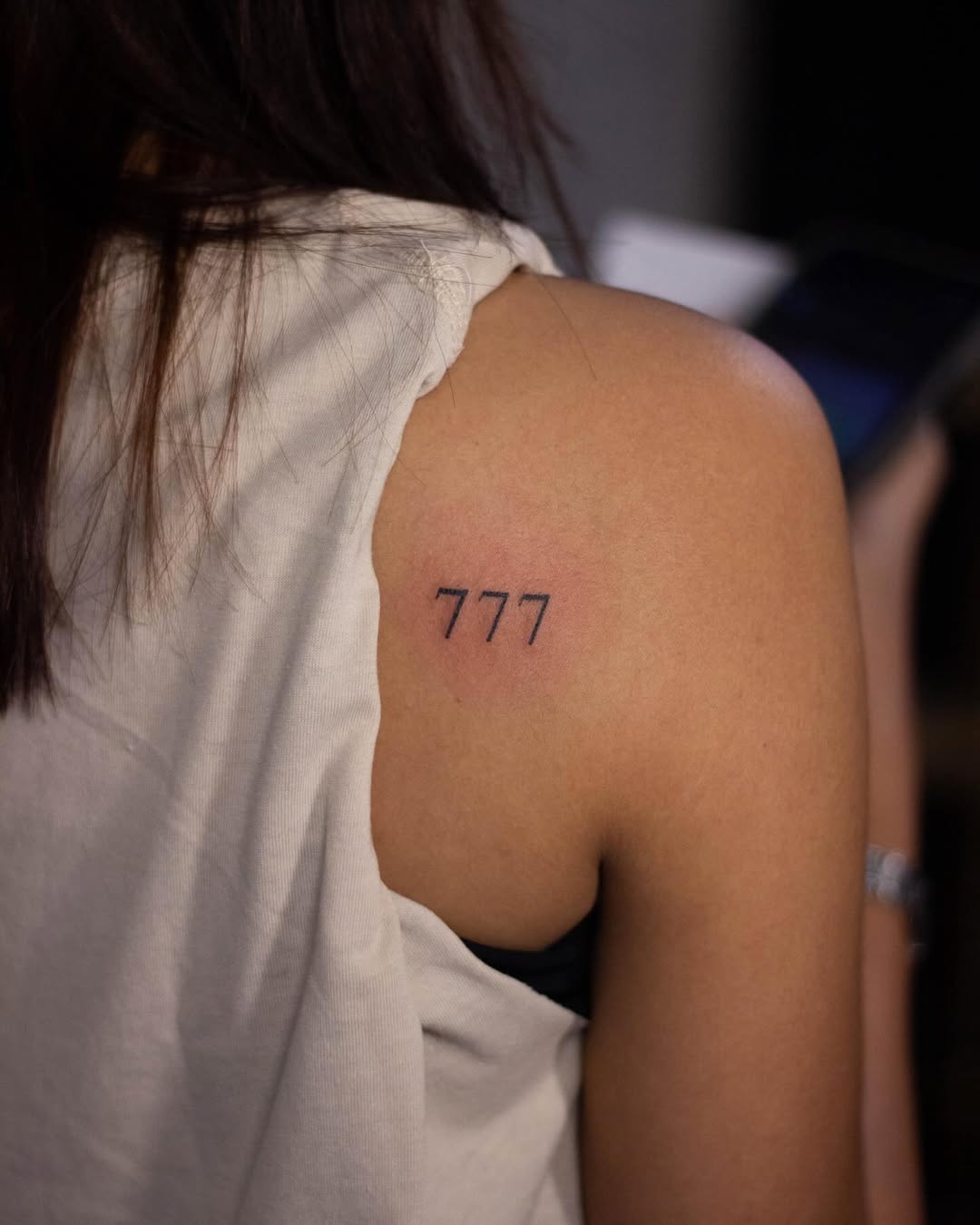 Minimalist 777 tattoo design on shoulder