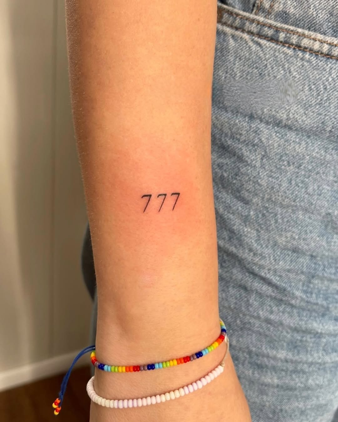 Minimalist 777 tattoo on wrist