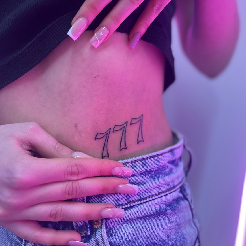 Stylish 777 tattoo nestled on the side