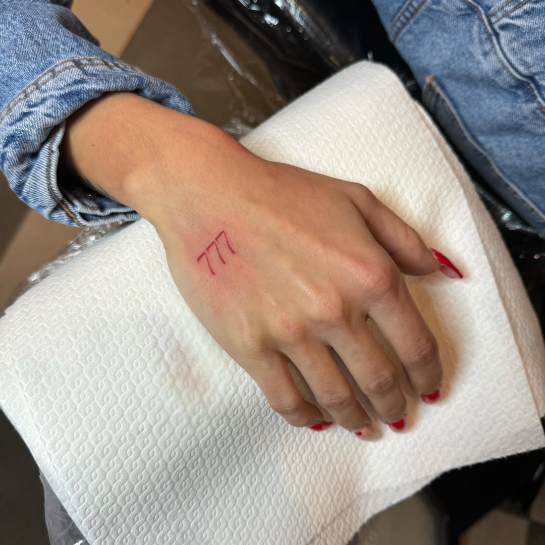 Stylish minimalist red 777 hand tattoo