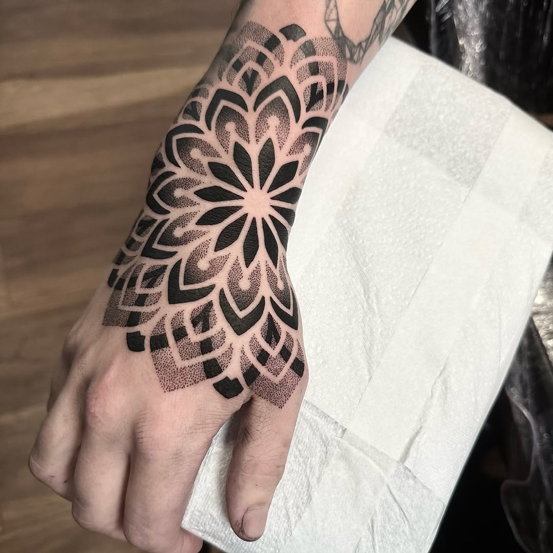 Intricate black ink mandala hand tattoo