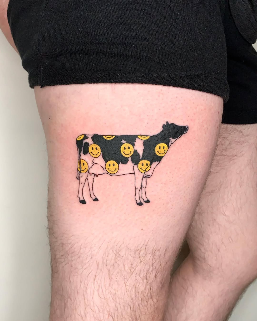 Whimsical cow tattoo with cheerful smilies