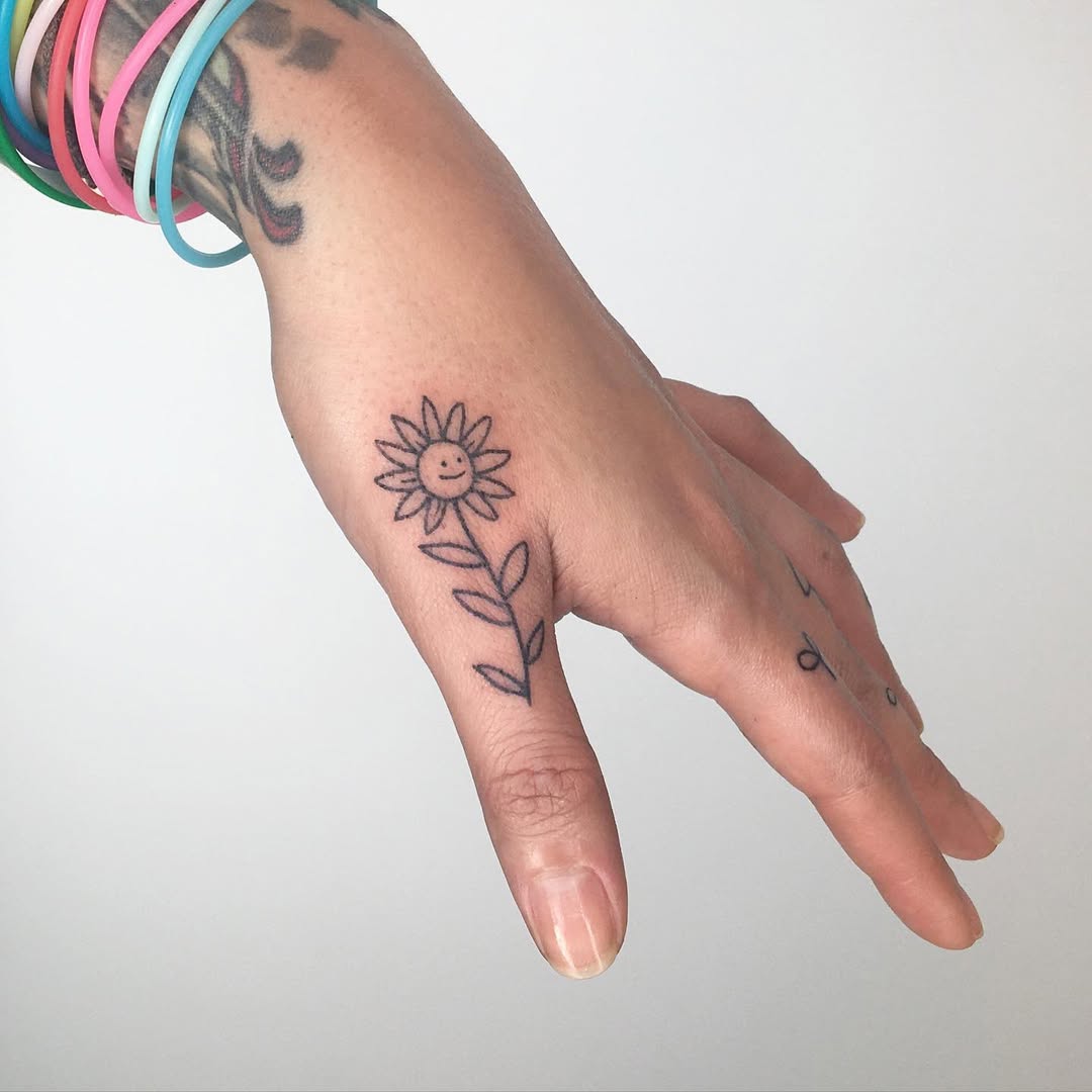 Charming smiling flower tattoo on hand