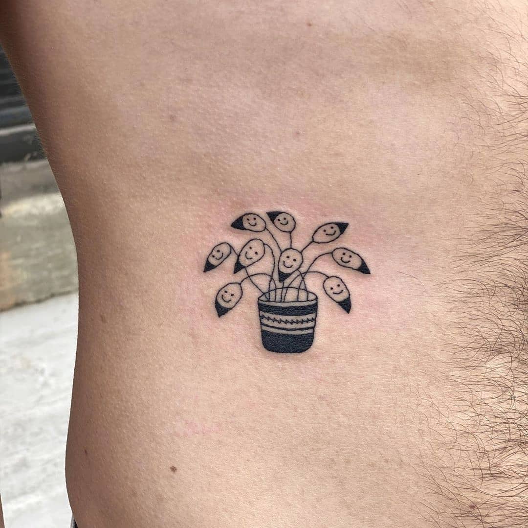 Whimsical plant with joyful faces tattoo
