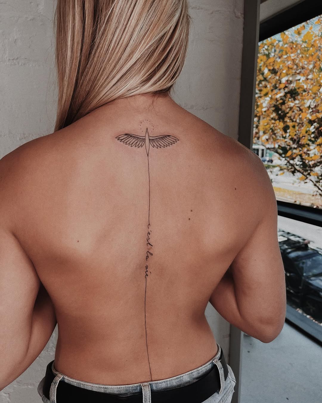 Elegant spine tattoo with wings and script