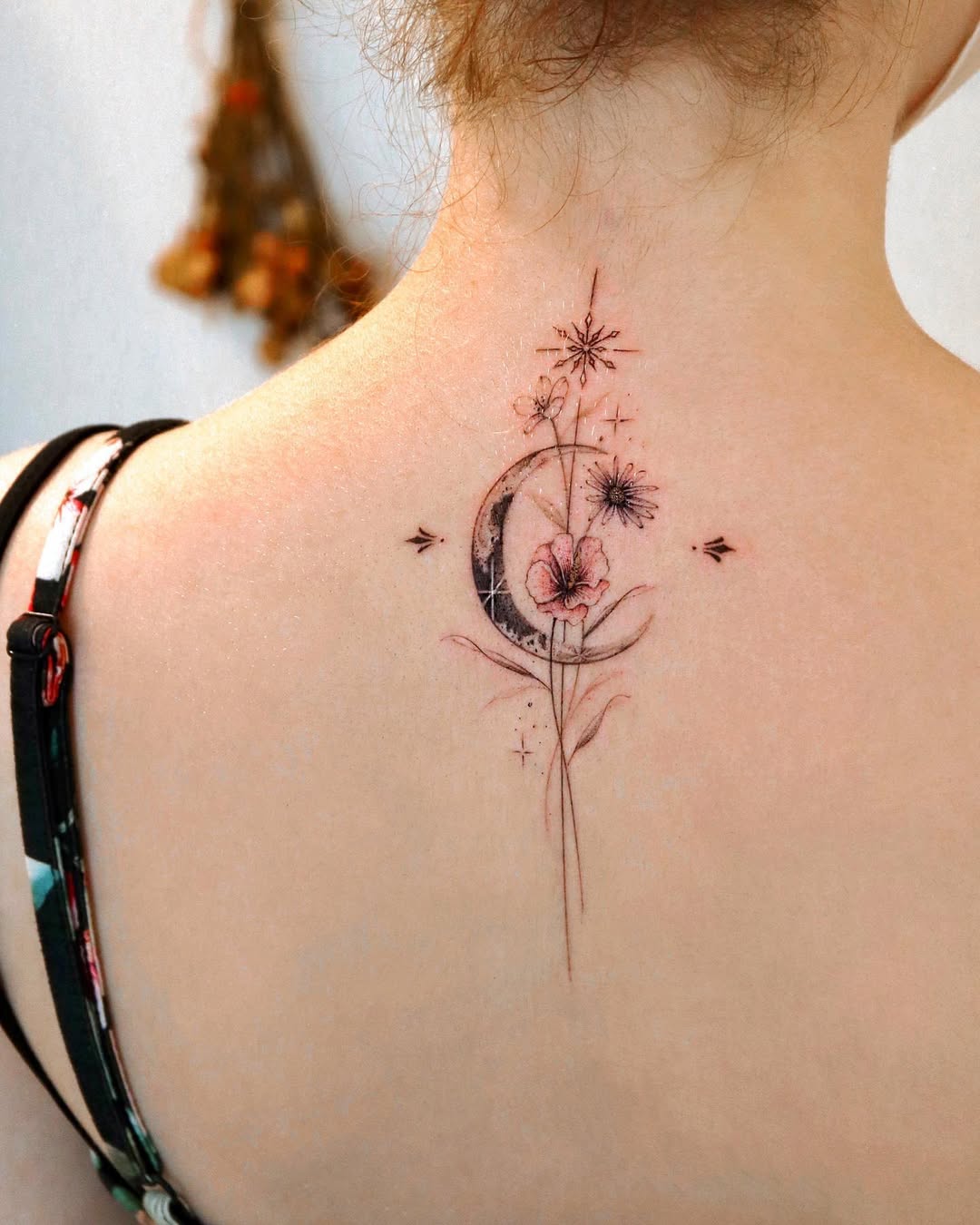 Delicate moon and floral spine tattoo design