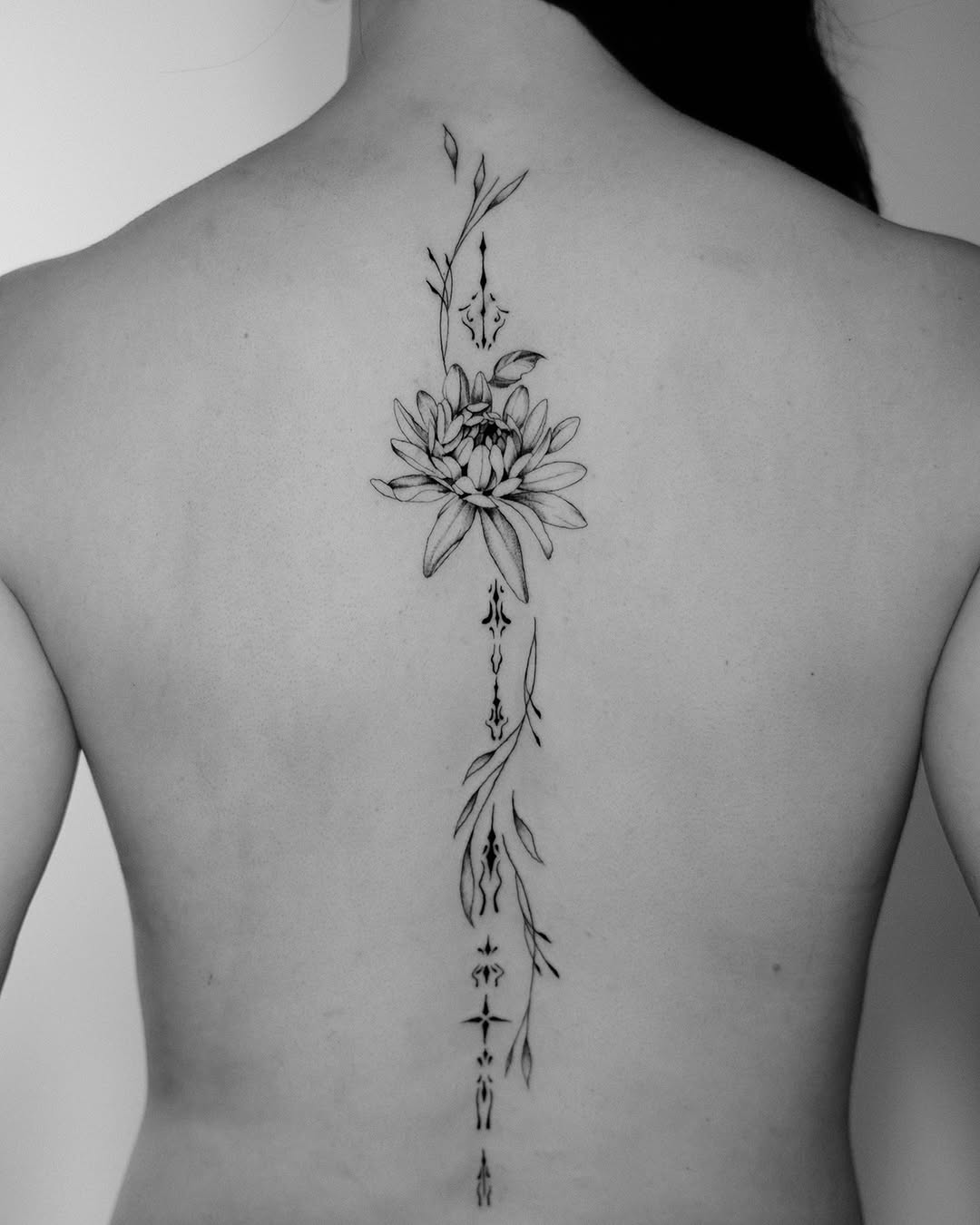 Elegant floral spine tattoo design in black ink