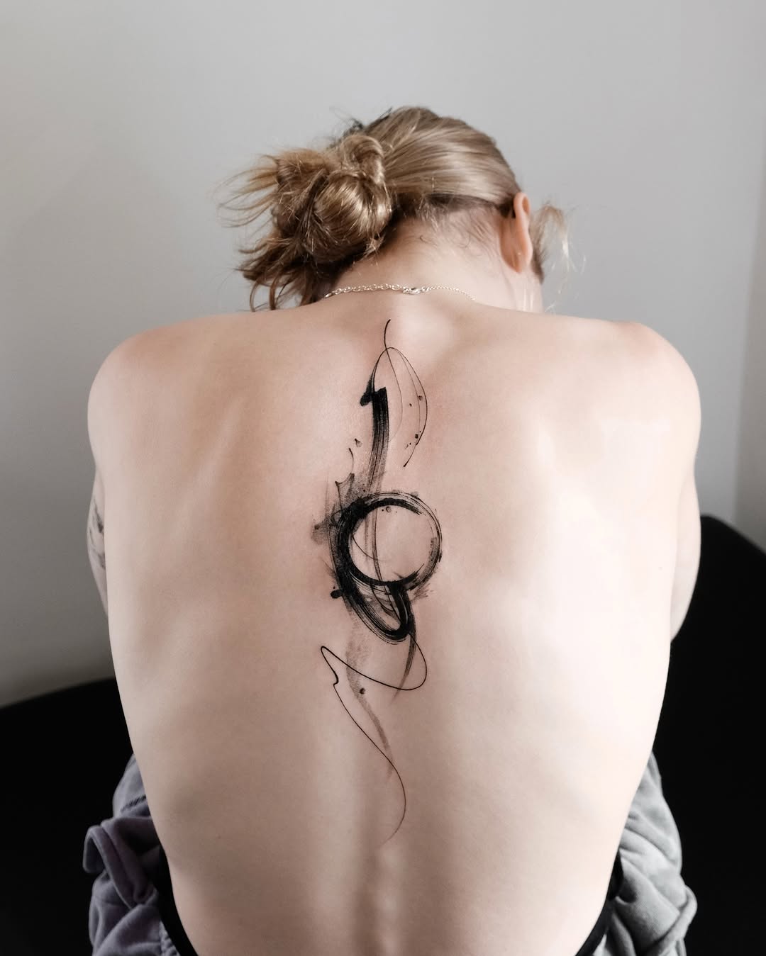 Sleek minimalist spine tattoo with abstract design